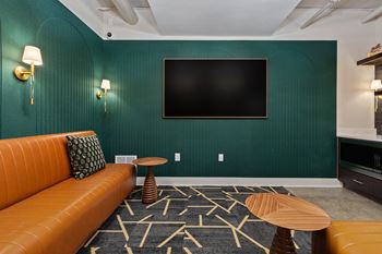 Media room with teal accent wall and orange leather sofa
